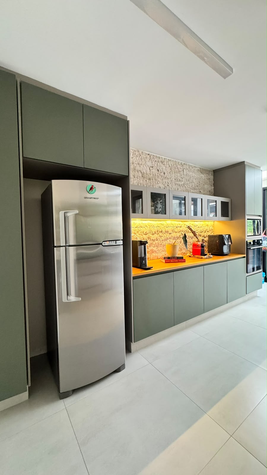Cozinha com armários verdes e bancada de madeira